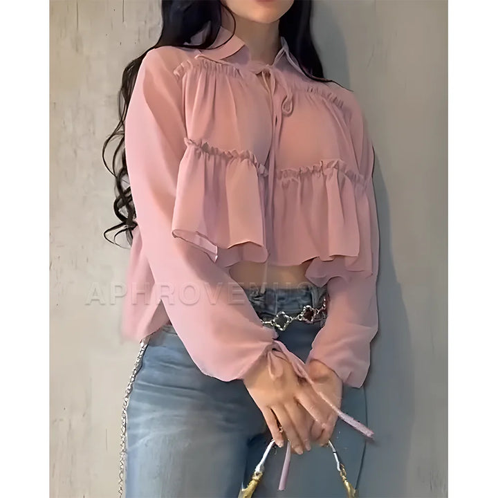Person wearing a pink blouse and blue jeans against a neutral background