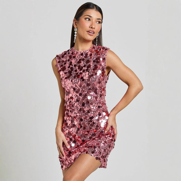 Woman wearing a pink sequin dress against a gray background